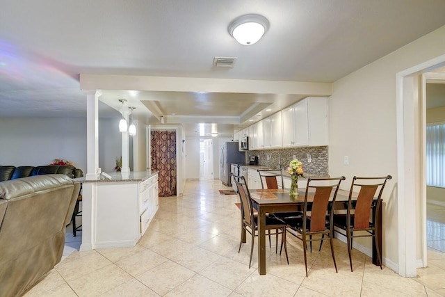 dining space featuring a healthy amount of sunlight, a tray ceiling, visible vents, and light tile patterned floors