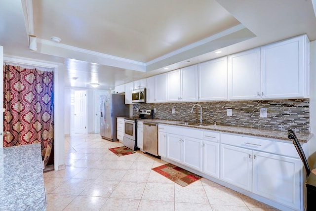 kitchen with a tray ceiling, sink, white cabinets, stainless steel appliances, and backsplash