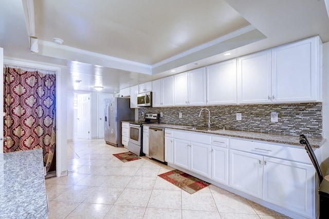 kitchen featuring stainless steel appliances, a sink, crown molding, decorative backsplash, and white cabinetry