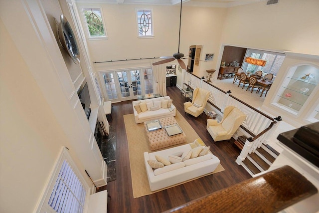 living room with a towering ceiling, ceiling fan, and dark wood-type flooring