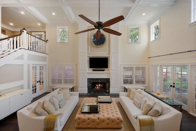 living room with a towering ceiling, hardwood / wood-style floors, beamed ceiling, and coffered ceiling