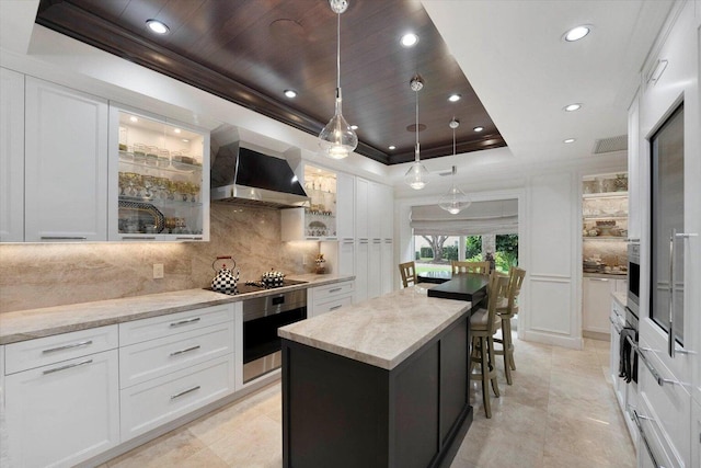 kitchen with white cabinetry, oven, a raised ceiling, and a center island