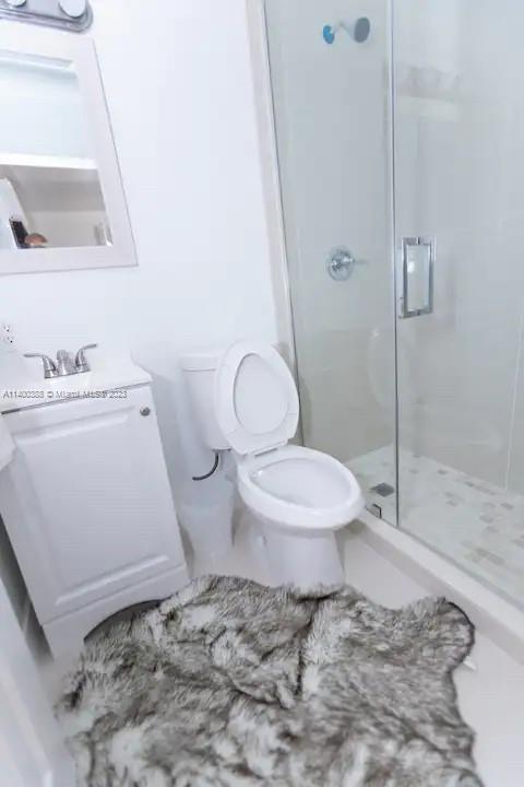 bathroom featuring a shower with shower door and toilet