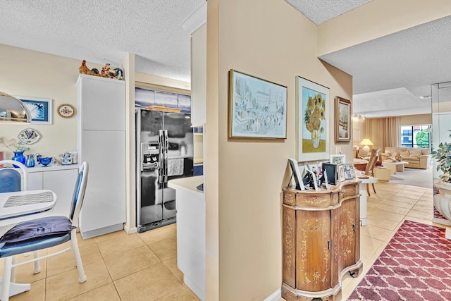 kitchen featuring a textured ceiling, fridge with ice dispenser, and light tile patterned floors