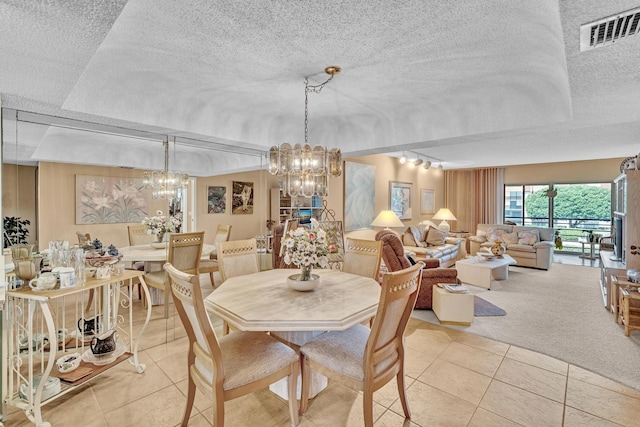 dining area featuring a textured ceiling, a tray ceiling, light tile patterned floors, and a notable chandelier