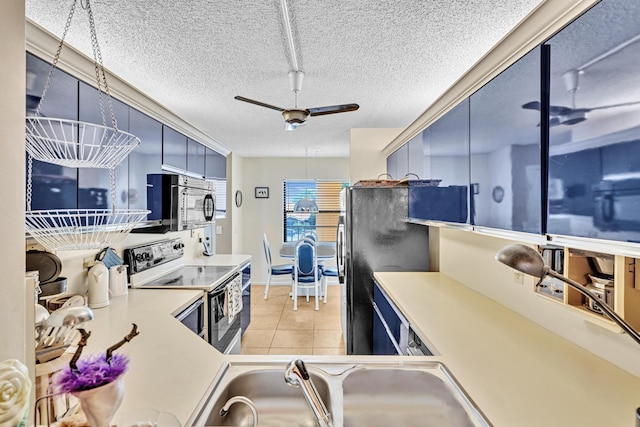 kitchen with stainless steel range with electric stovetop, black refrigerator, a textured ceiling, ceiling fan, and sink