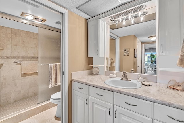 bathroom featuring a tile shower, a textured ceiling, tile patterned floors, vanity, and toilet