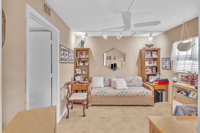 interior space with ceiling fan, a textured ceiling, light tile patterned floors, and rail lighting