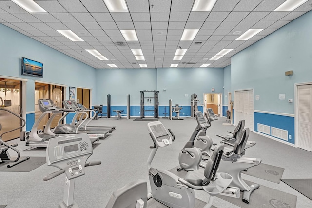 workout area featuring a drop ceiling and a towering ceiling