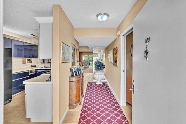 hallway with a textured ceiling and light tile patterned flooring