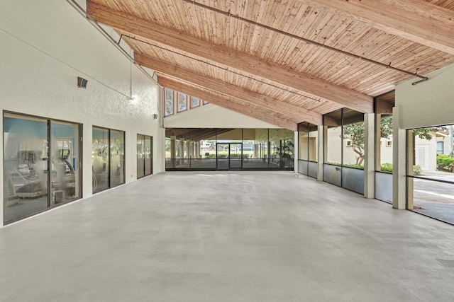 interior space featuring a healthy amount of sunlight, beam ceiling, concrete flooring, and high vaulted ceiling