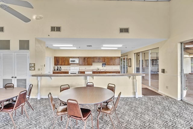 carpeted dining area featuring a high ceiling, sink, and ceiling fan