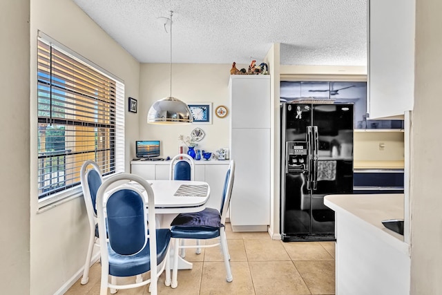 kitchen with white cabinets, black fridge with ice dispenser, hanging light fixtures, and a textured ceiling