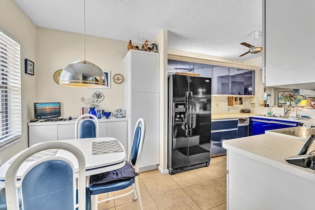 kitchen featuring blue cabinets, a textured ceiling, ceiling fan, decorative light fixtures, and black fridge