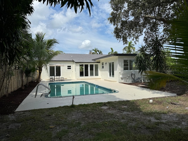 rear view of property featuring a fenced in pool and a patio area