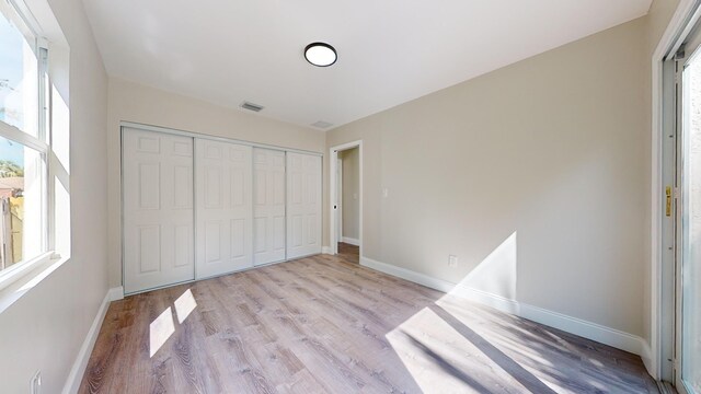 unfurnished bedroom with a closet and light hardwood / wood-style floors