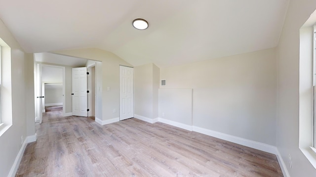 empty room featuring light wood-type flooring and lofted ceiling