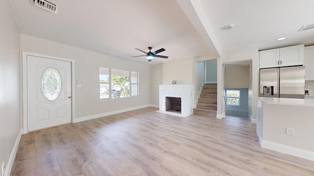 foyer with light wood-type flooring, a fireplace, and ceiling fan