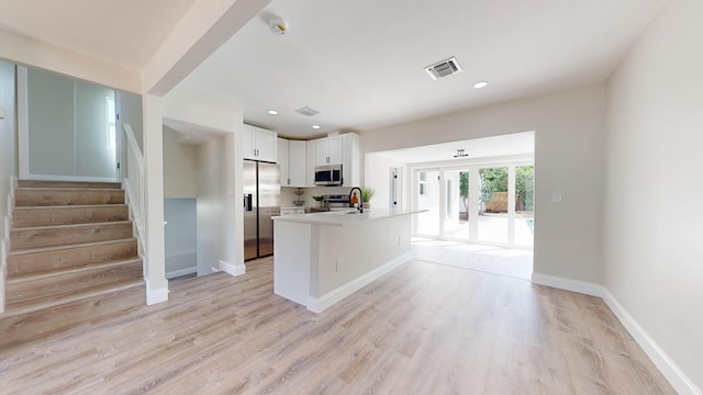 kitchen featuring appliances with stainless steel finishes, a center island with sink, light hardwood / wood-style flooring, and white cabinets