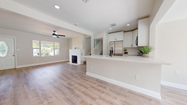 kitchen with ceiling fan, kitchen peninsula, white cabinetry, stainless steel appliances, and light wood-type flooring