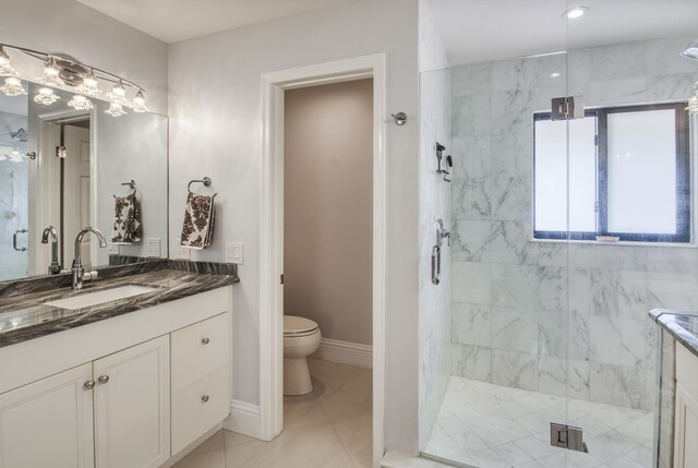 bathroom featuring tile patterned flooring, vanity, toilet, and a shower with door