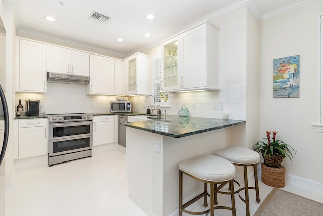 kitchen with stainless steel appliances, kitchen peninsula, and white cabinetry