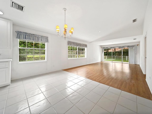 tiled empty room featuring an inviting chandelier and lofted ceiling