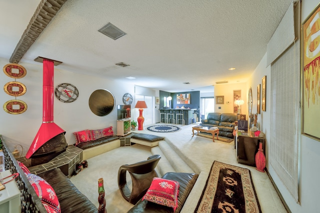 living room featuring light carpet, indoor bar, and a textured ceiling