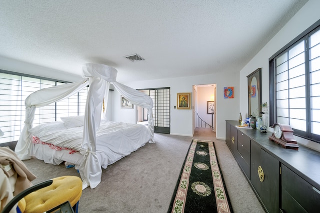 carpeted bedroom featuring a textured ceiling and multiple windows