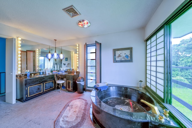 bathroom featuring vanity, a bathtub, a notable chandelier, and a textured ceiling