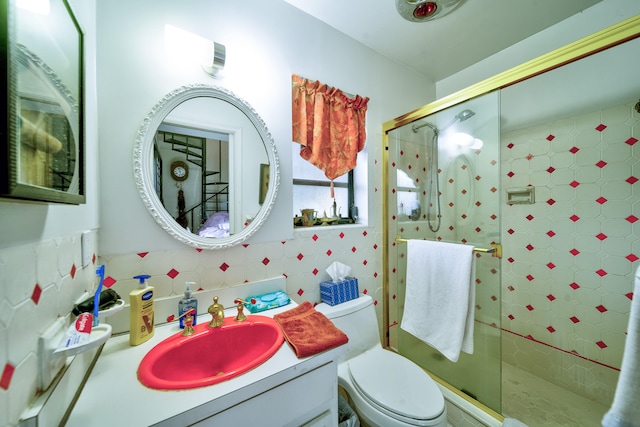 bathroom featuring vanity, tile walls, toilet, and a shower with door