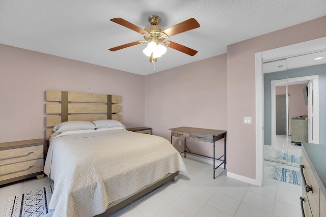 bedroom with ceiling fan, light tile patterned floors, and a textured ceiling