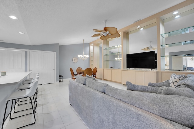 tiled living room with ceiling fan with notable chandelier, vaulted ceiling, and a textured ceiling