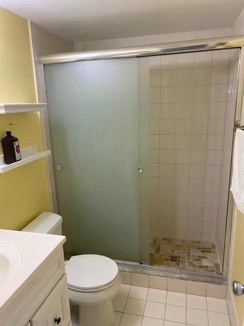 bathroom featuring vanity, tile patterned flooring, toilet, and a shower with door