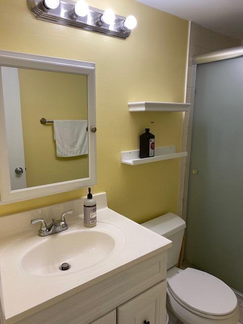 bathroom featuring vanity, an enclosed shower, and toilet