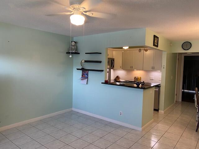 kitchen with light tile patterned floors, kitchen peninsula, ceiling fan, and tasteful backsplash