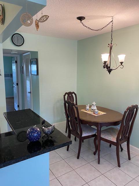 tiled dining area featuring an inviting chandelier and a textured ceiling