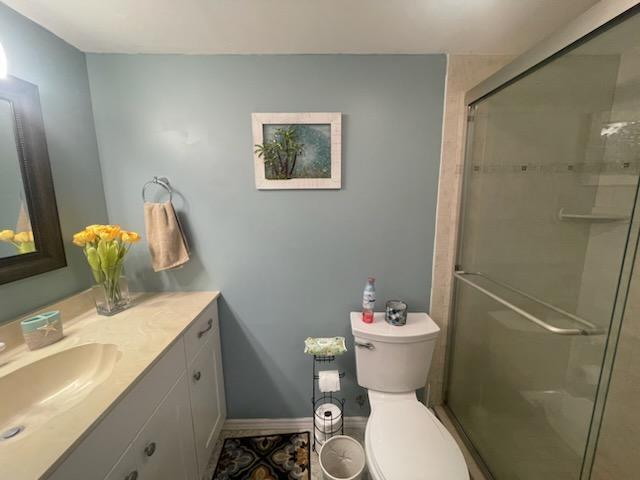 full bathroom featuring toilet, a shower stall, baseboards, and vanity