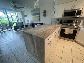 kitchen featuring stainless steel appliances, tile patterned flooring, light countertops, and a peninsula