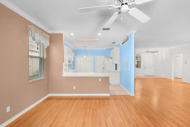 unfurnished living room with crown molding, ceiling fan, and light wood-type flooring