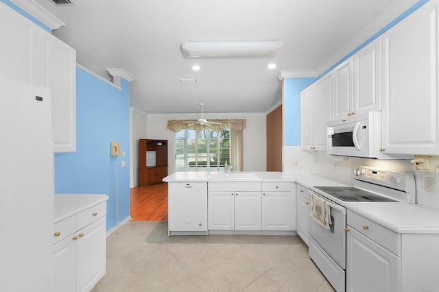 kitchen featuring sink, kitchen peninsula, white appliances, decorative backsplash, and white cabinets