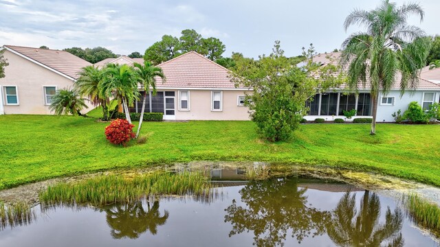 rear view of property with a water view and a yard