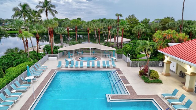 view of swimming pool with a community hot tub, a patio, and a water view