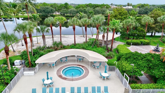 view of swimming pool featuring a water view, a hot tub, and a patio