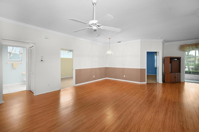 empty room featuring a healthy amount of sunlight, crown molding, light hardwood / wood-style flooring, and ceiling fan