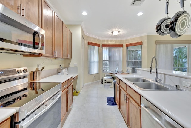 kitchen with light tile patterned flooring, ornamental molding, sink, and appliances with stainless steel finishes