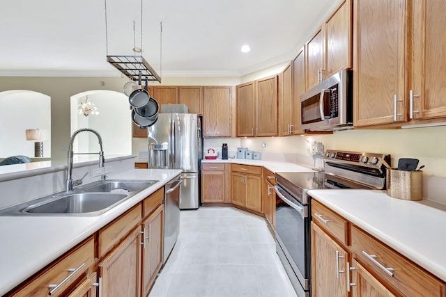 kitchen with appliances with stainless steel finishes, crown molding, sink, light tile patterned floors, and a notable chandelier