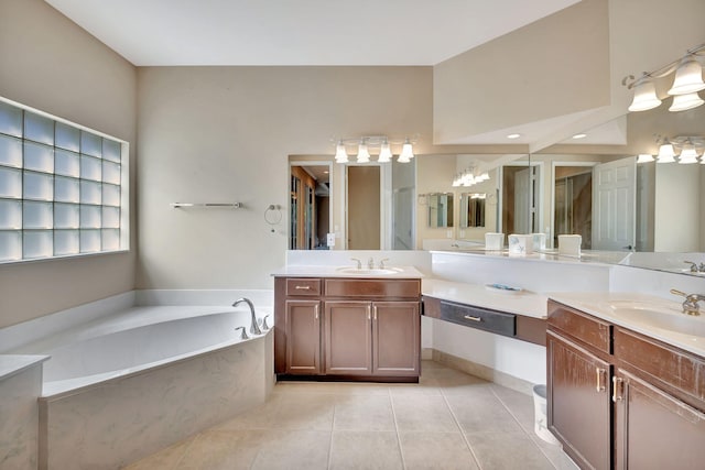 bathroom with tiled tub, tile patterned flooring, and vanity