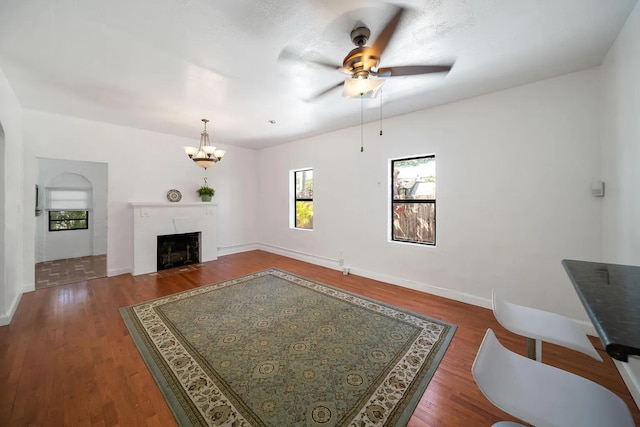 living room with ceiling fan with notable chandelier and dark hardwood / wood-style flooring