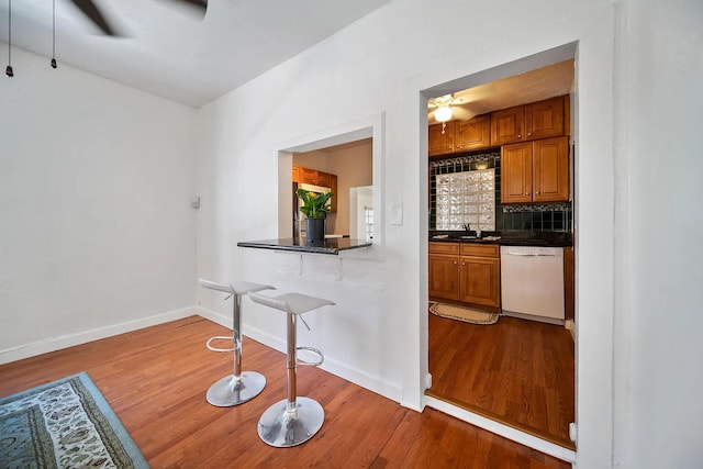 kitchen featuring decorative backsplash, light hardwood / wood-style floors, dishwasher, and ceiling fan